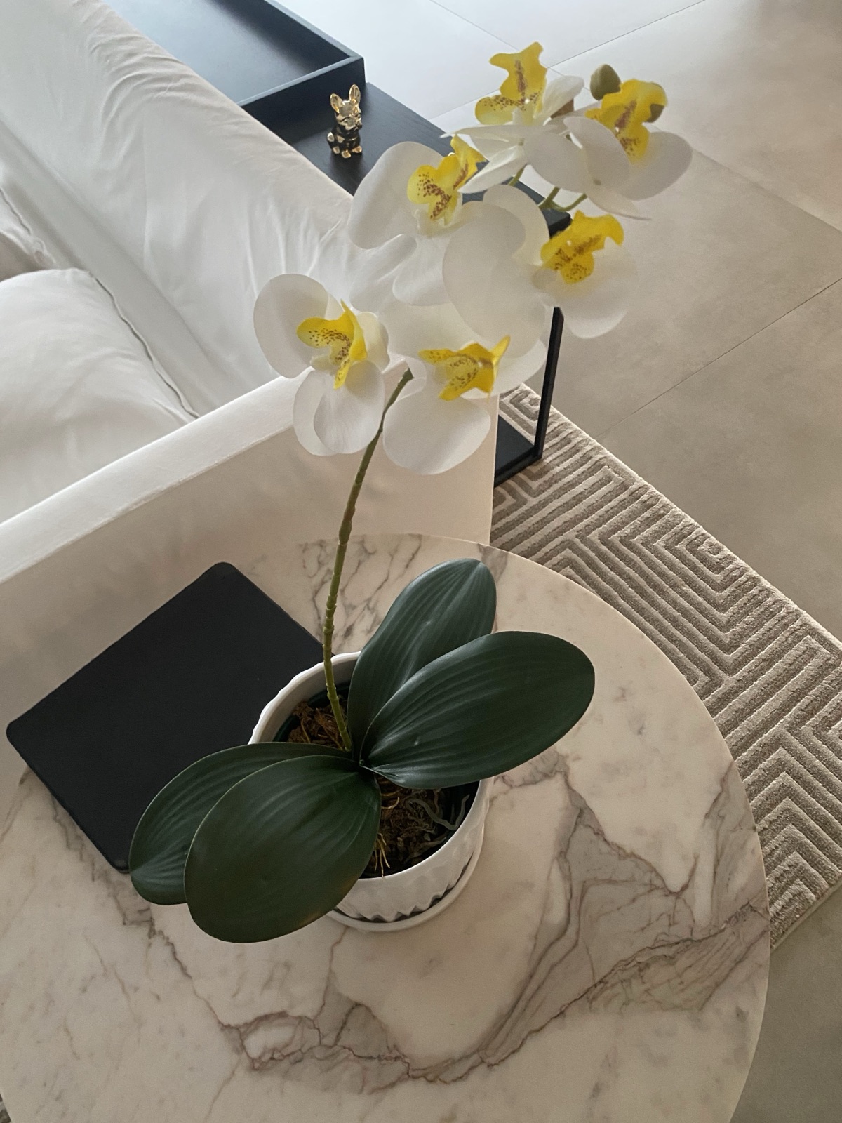 Arranjo de orquídea branca artificial sobre mesa de mármore