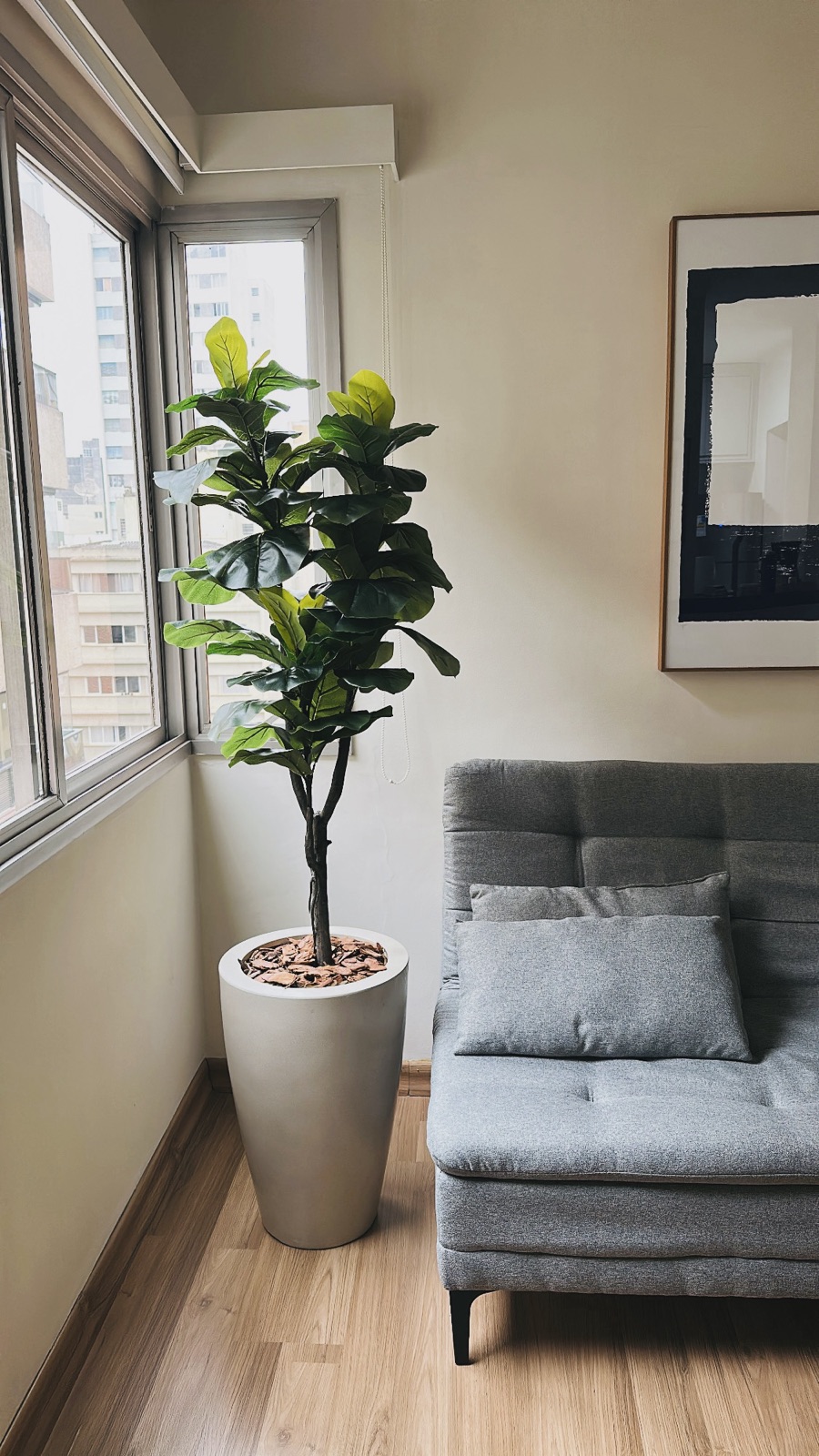 Ficus Lyrata artificial em vaso, ao lado do sofá numa sala de estar