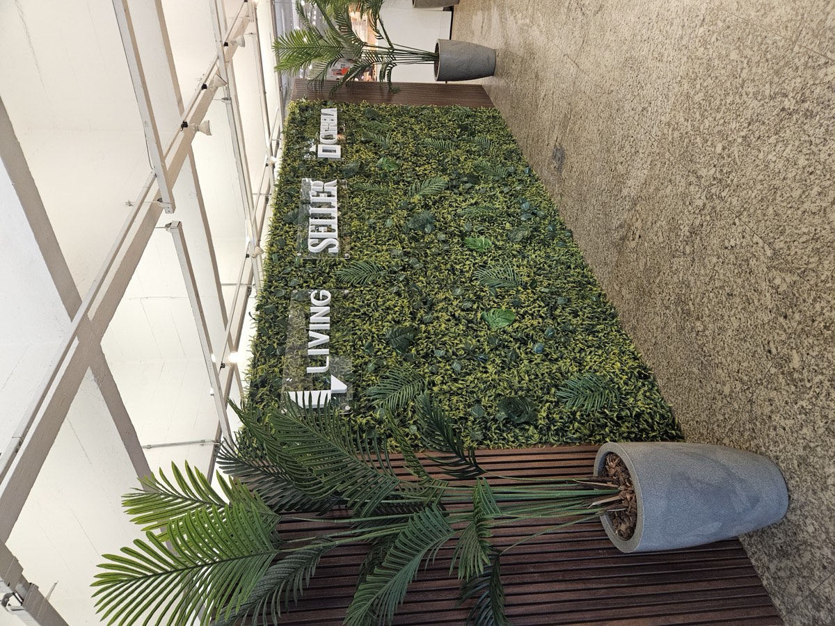 Painel de jardim vertical com palmeiras ao lado, na sala de vendas Living Seller