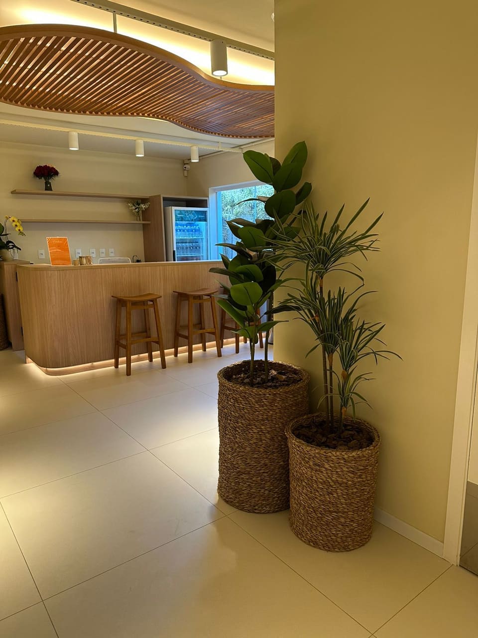 Café corporativo com duas plantas artificiais em cachepôs de fibra natural